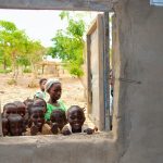 African kids peeking through the window of their schoolbuilding